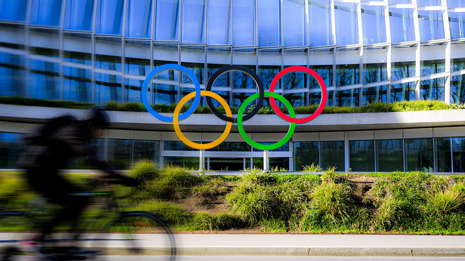 Die olympischen Ringe vor einem Gebäude. 