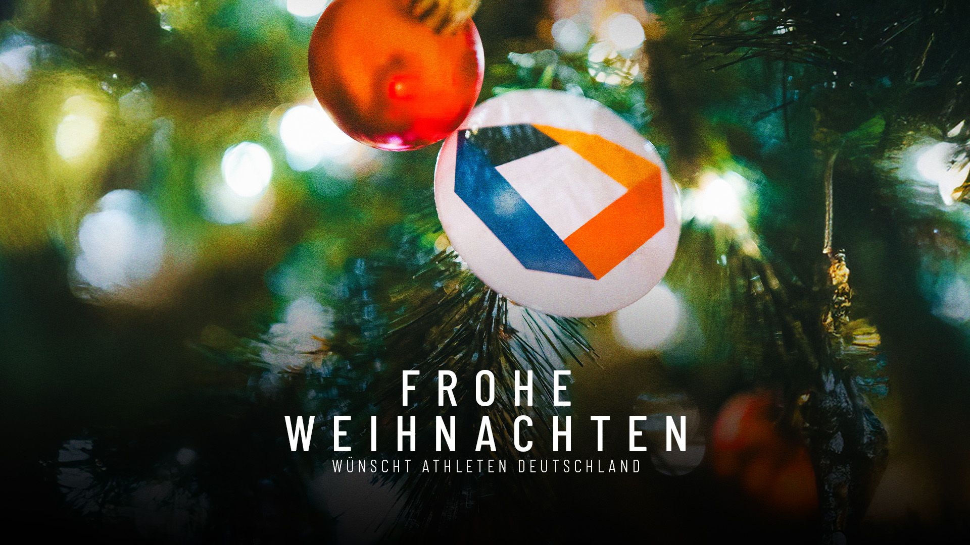 Eine Christbaumkugel am Baum neben dem Logo von Athleten Deutschland.